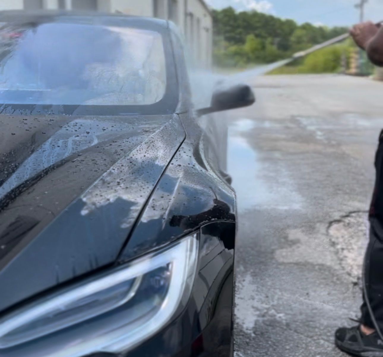 a man is washing a black car with a high pressure washer .