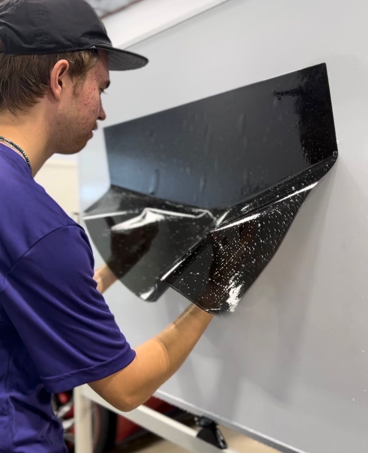 a man in a purple shirt is holding a piece of black paper
