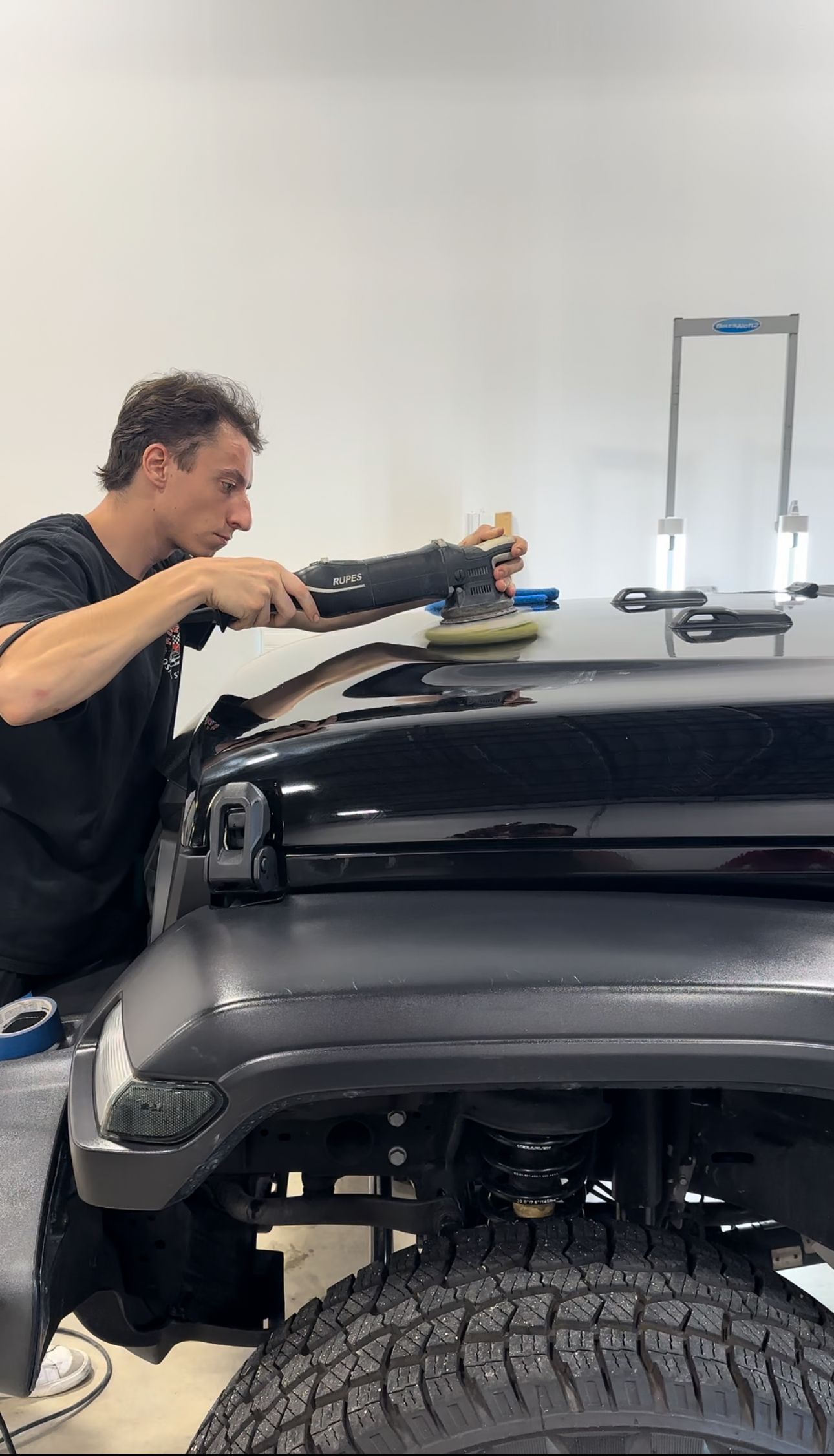 a man is polishing the hood of a jeep in a garage .