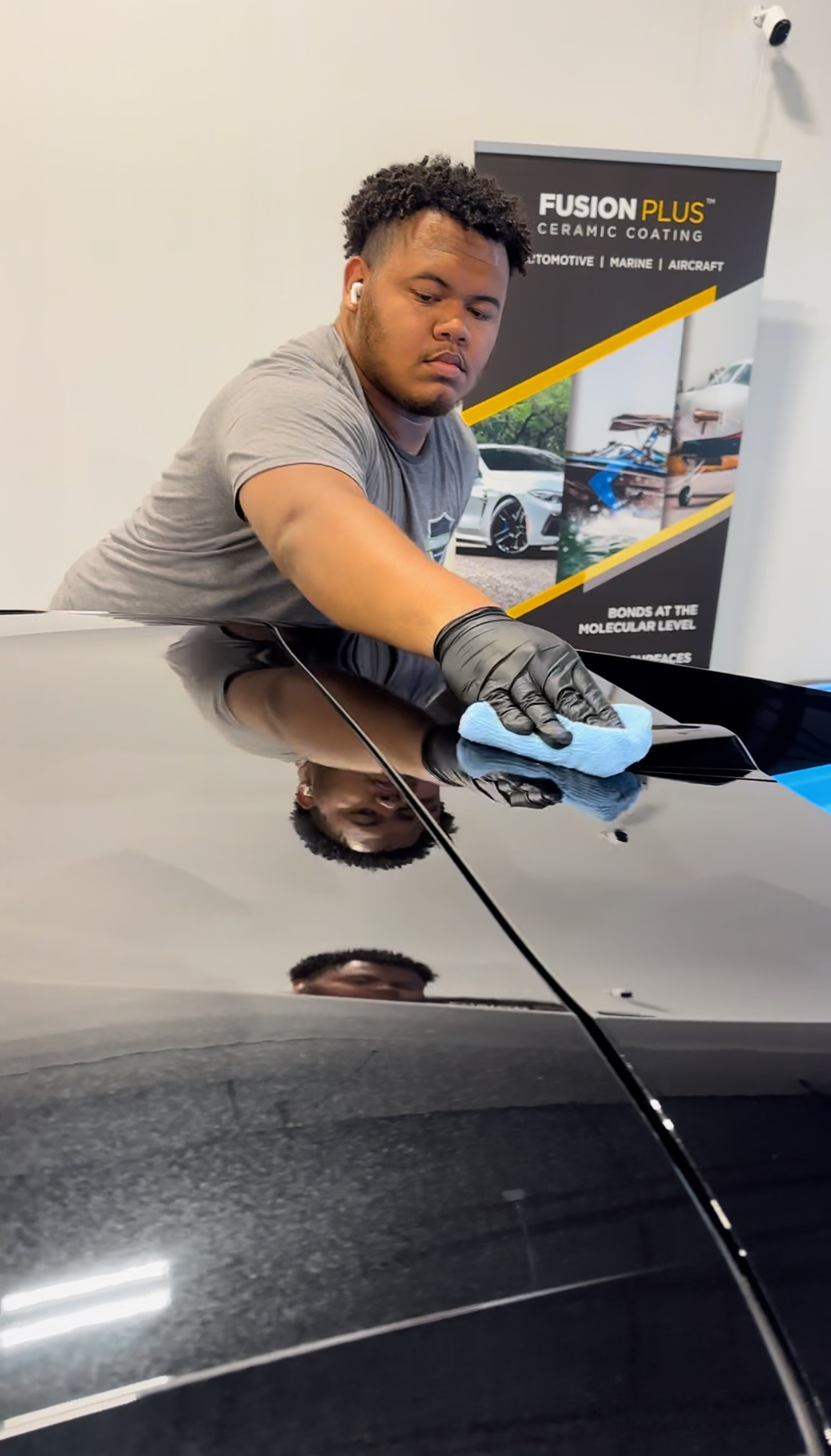 a man is cleaning the hood of a car with a cloth .
