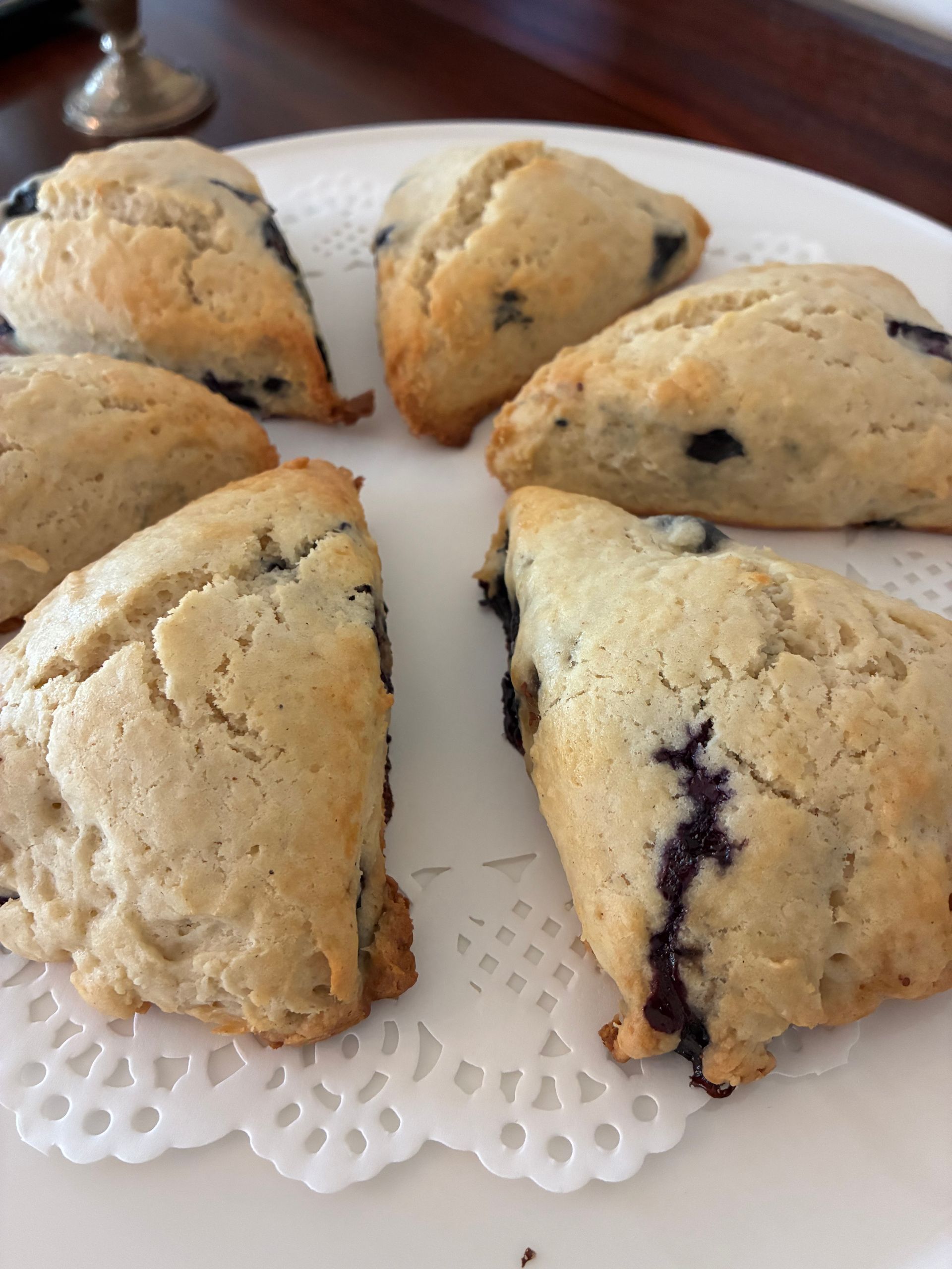 Freshly baked blueberry scones, cut into triangle wedges, sitting on cake stand platter