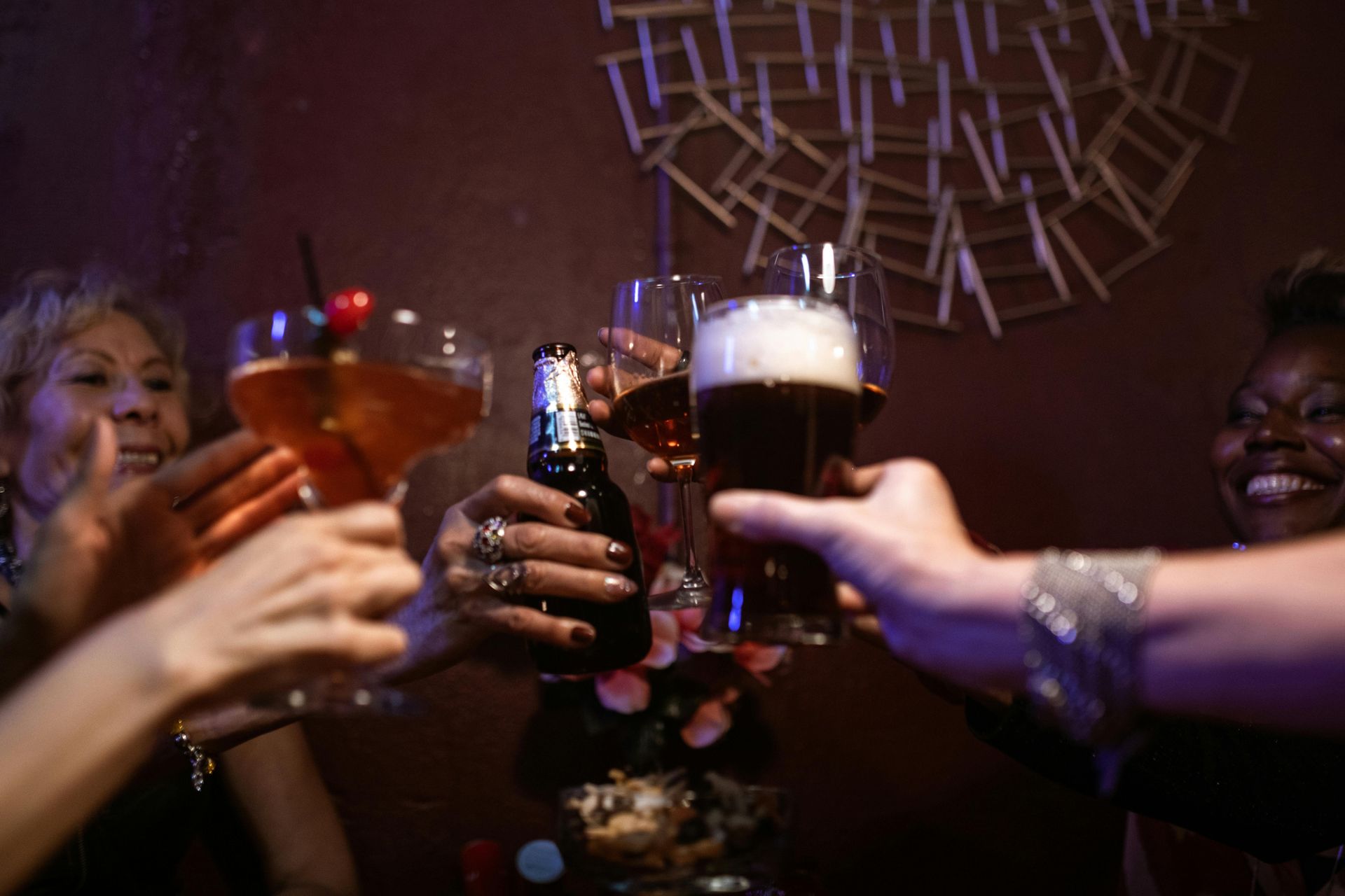 People toasting drinks in a dimly lit bar, cheers, smiles.