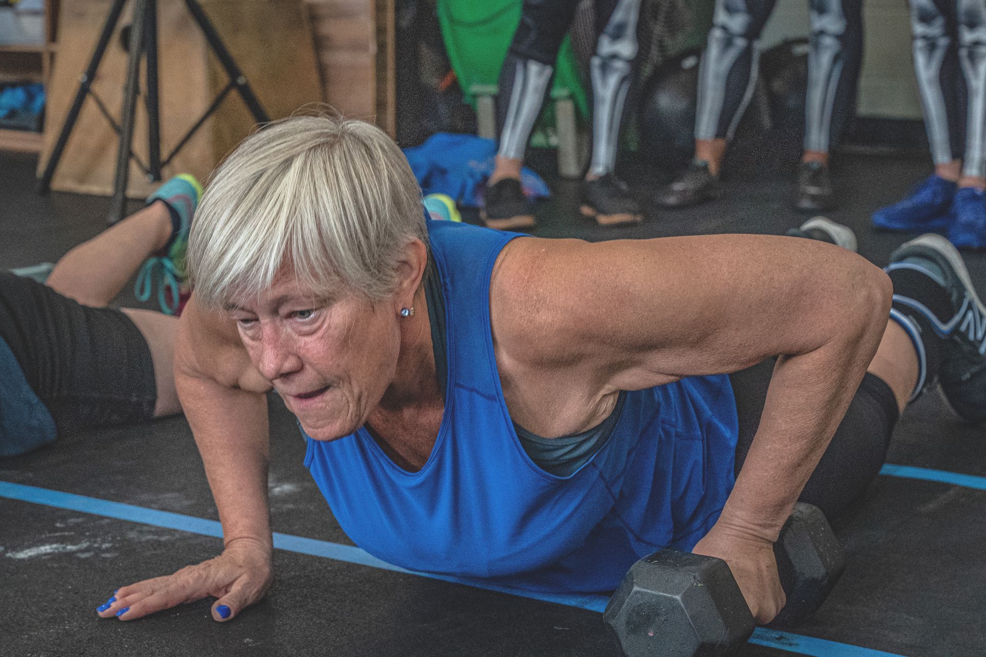 A woman is doing push ups with a dumbbell in a gym.