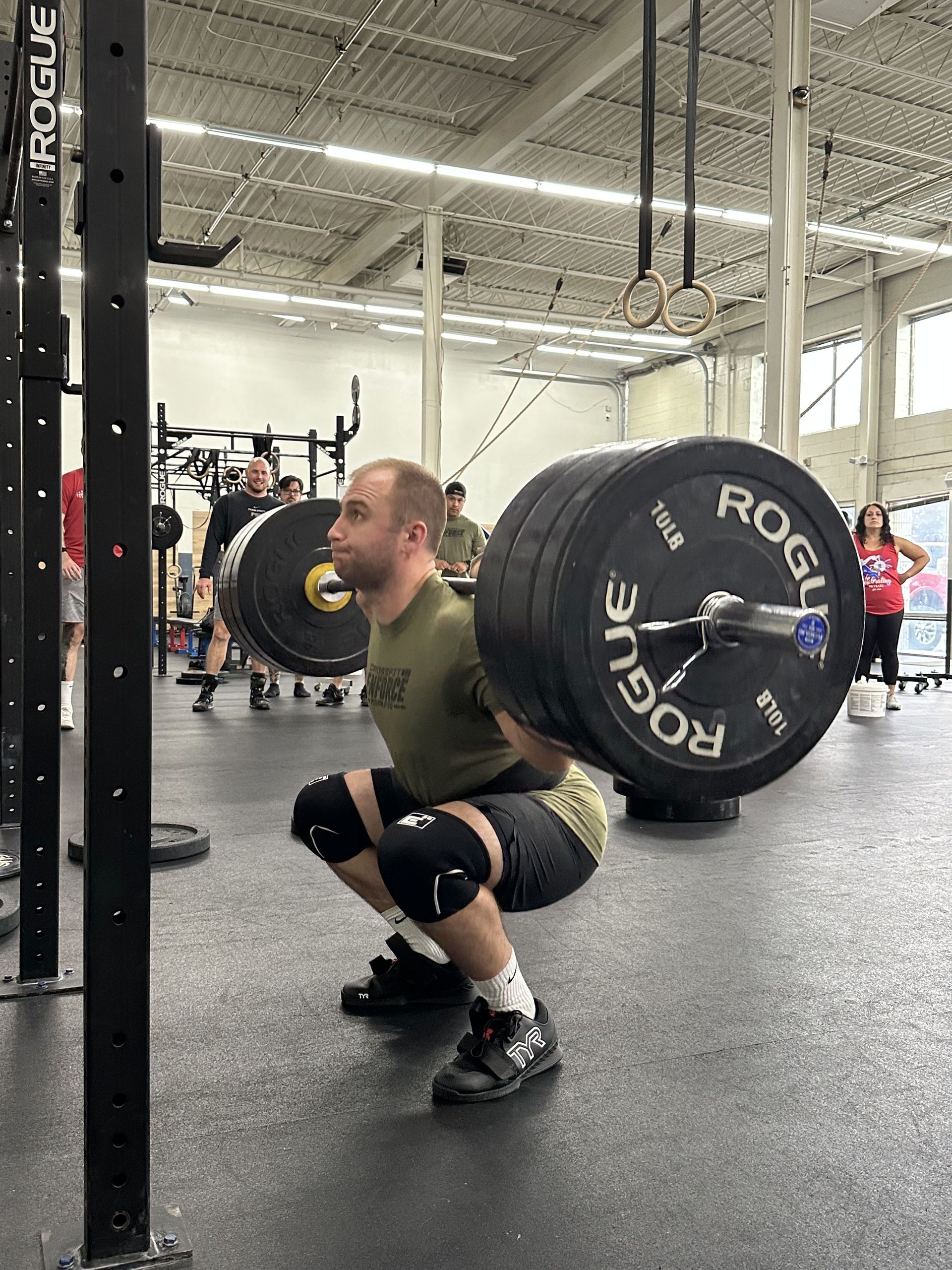 A man is squatting with a barbell in a gym.