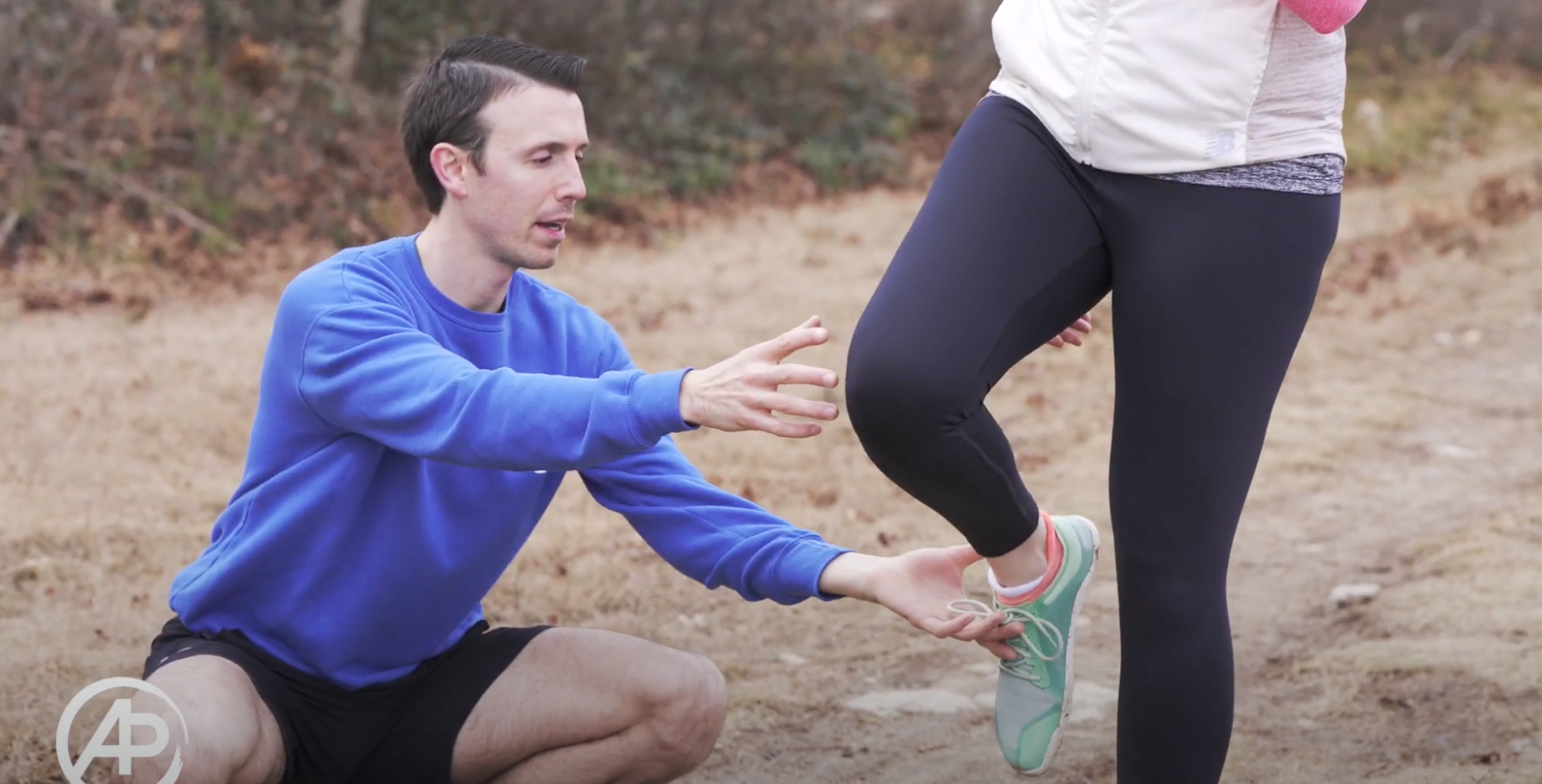 A man is helping a woman stretch her leg.