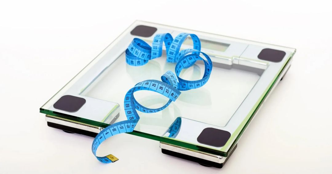 A measuring tape is laying on top of a scale.
