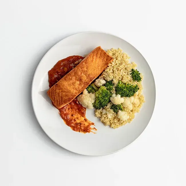 A white plate topped with salmon , broccoli , rice and sauce.