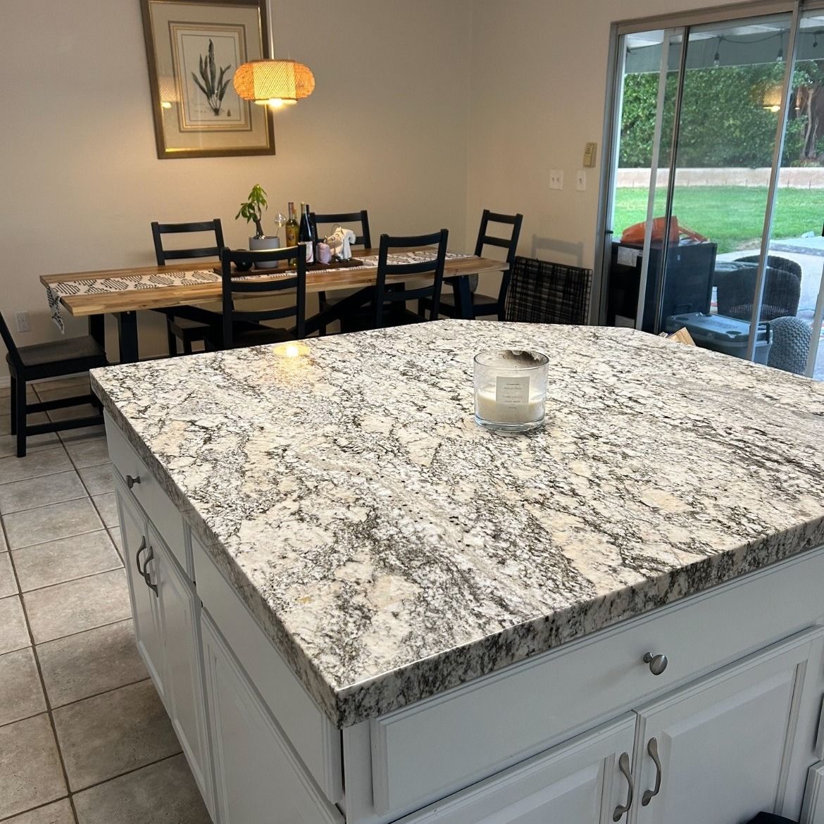 Kitchen with granite countertop island, dining table, and sliding glass door to a patio.
