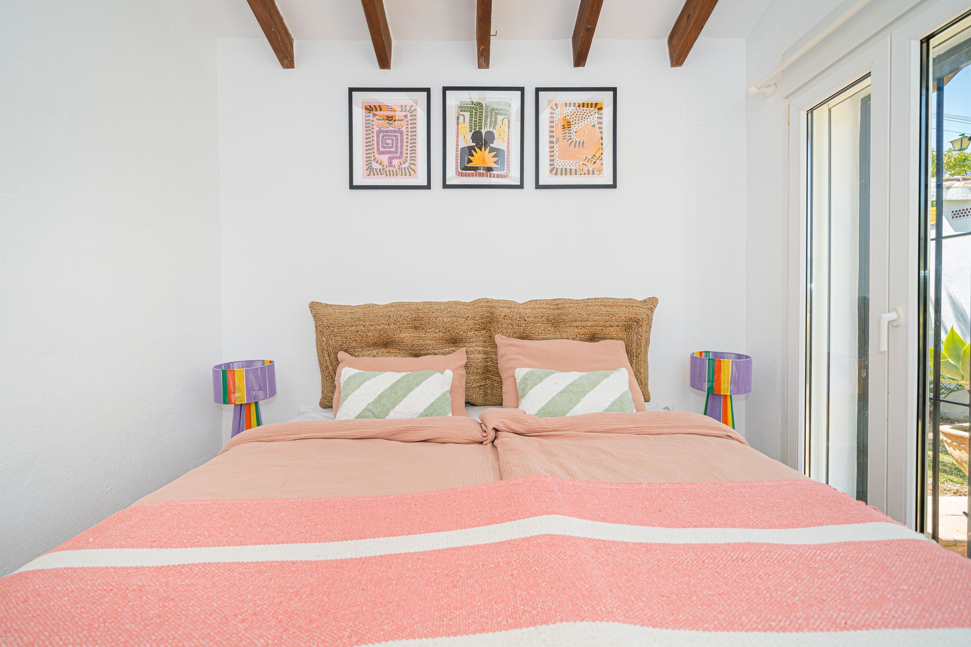 Een slaapkamer met een bed en drie schilderijen aan de muur
