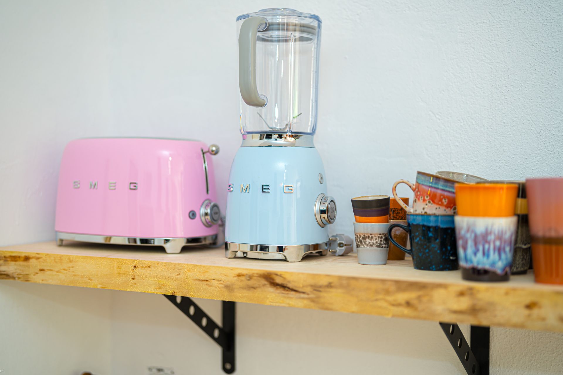 Een roze broodrooster en een blauwe blender staan ​​op een houten plank van Villa Fave in Javea 