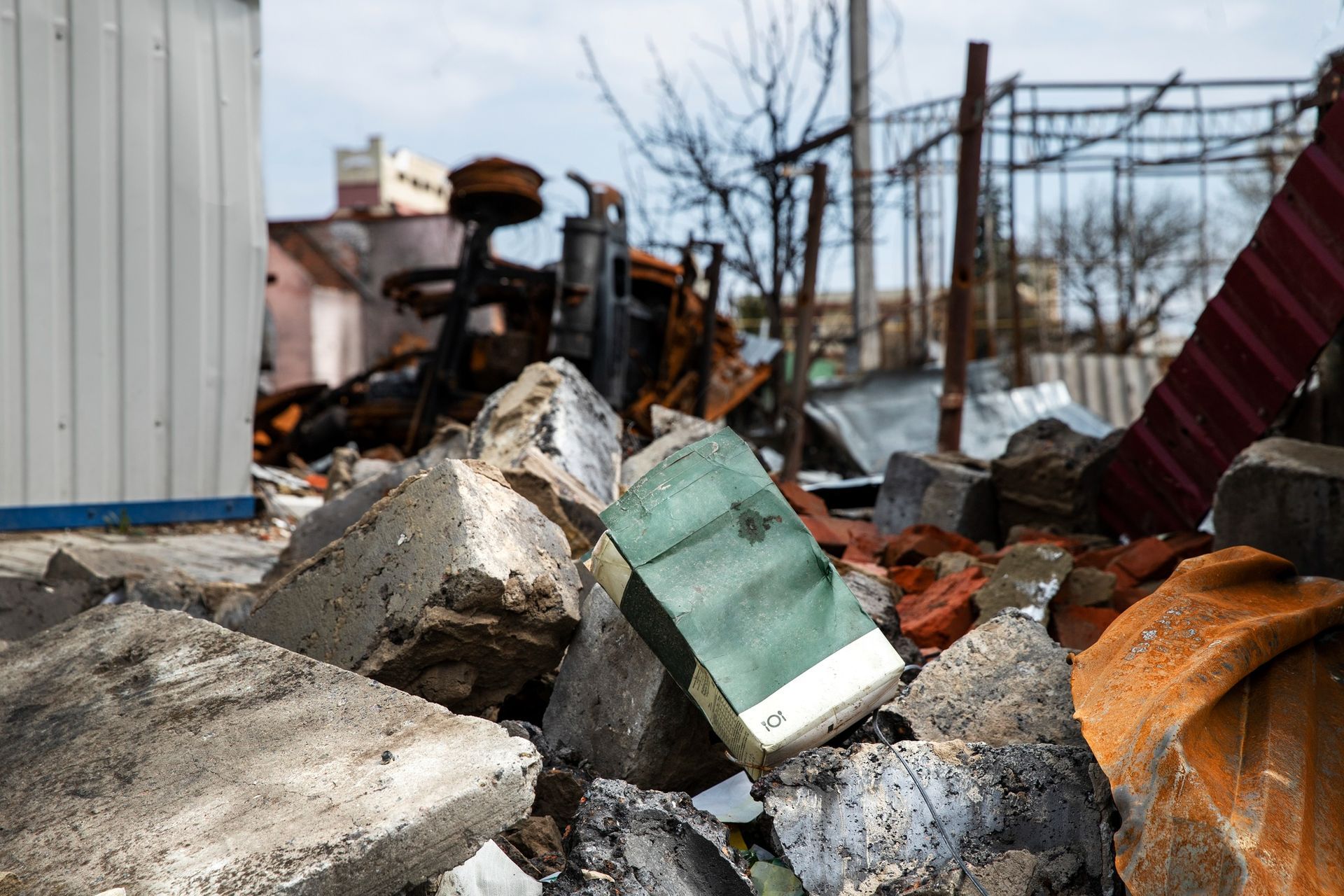 Rubble and twisted metal at a fire-damaged site, with a green appliance amid debris.