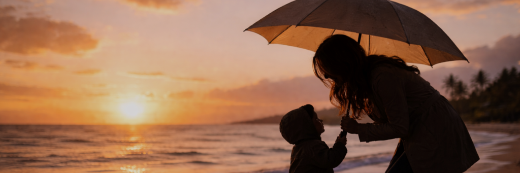Silhouette of a person and child sharing an umbrella at sunset on a beach
