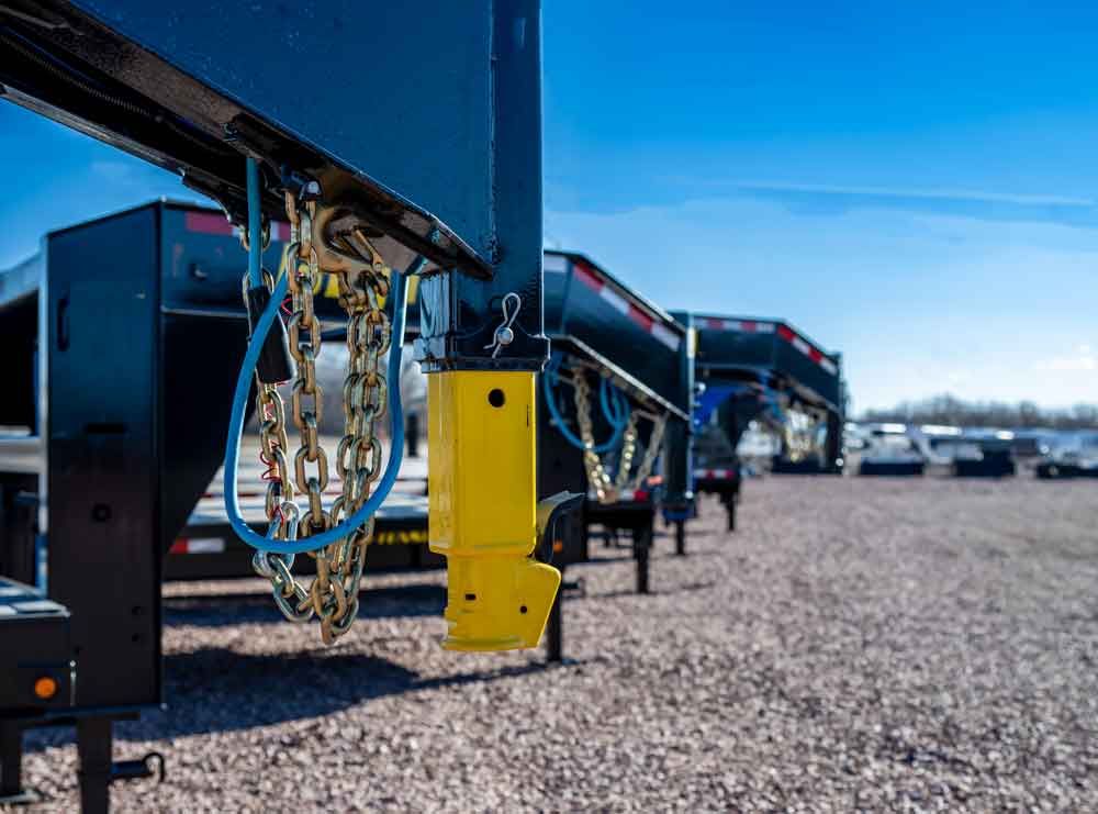 Row of blue industrial machines with yellow control boxes on a gravel lot under a clear sky