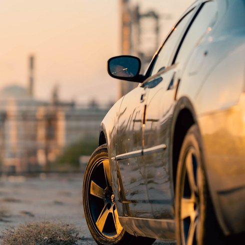 Silver car parked at sunset with city buildings in the background