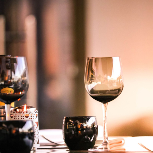 Wine glasses and candlelit table setting with warm, soft lighting