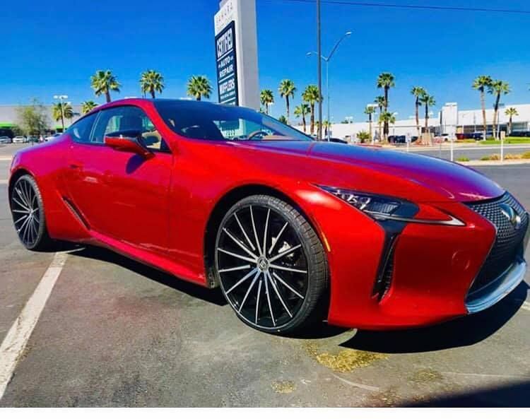 Red Lexus sports coupe parked outdoors on a sunny day with palm trees in the background