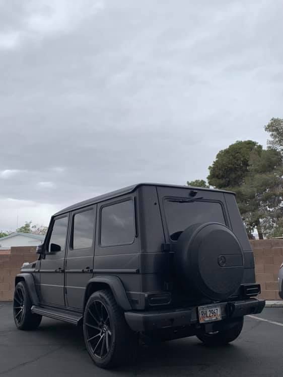 Black Mercedes G-Class SUV parked outdoors under a cloudy sky.