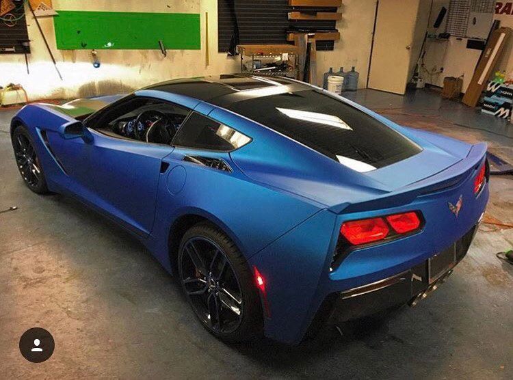 Blue sports car parked in a garage, viewed from the rear-left side.