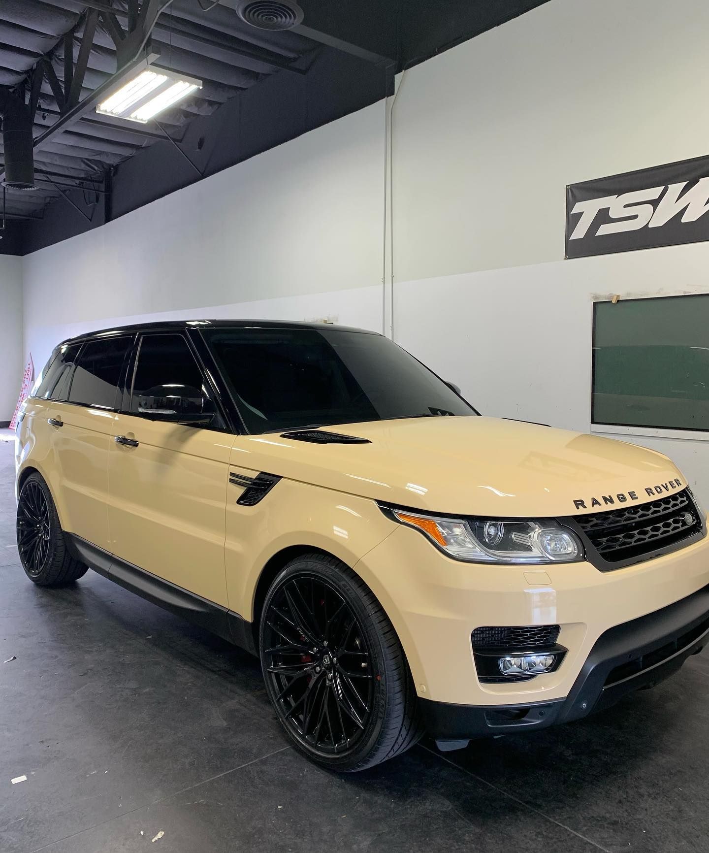 Tan Range Rover SUV with black wheels parked indoors in a showroom