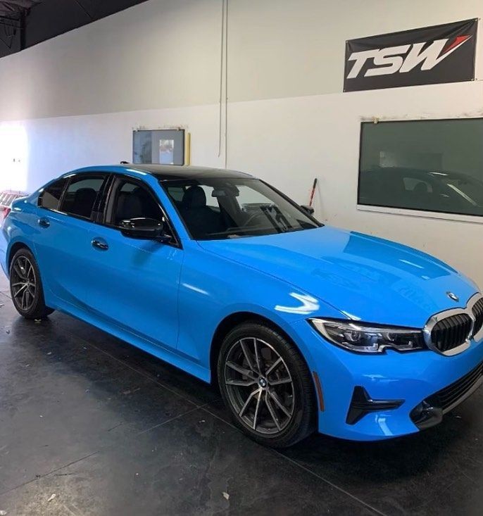 Bright blue BMW sedan in a showroom with TSW signage on the wall