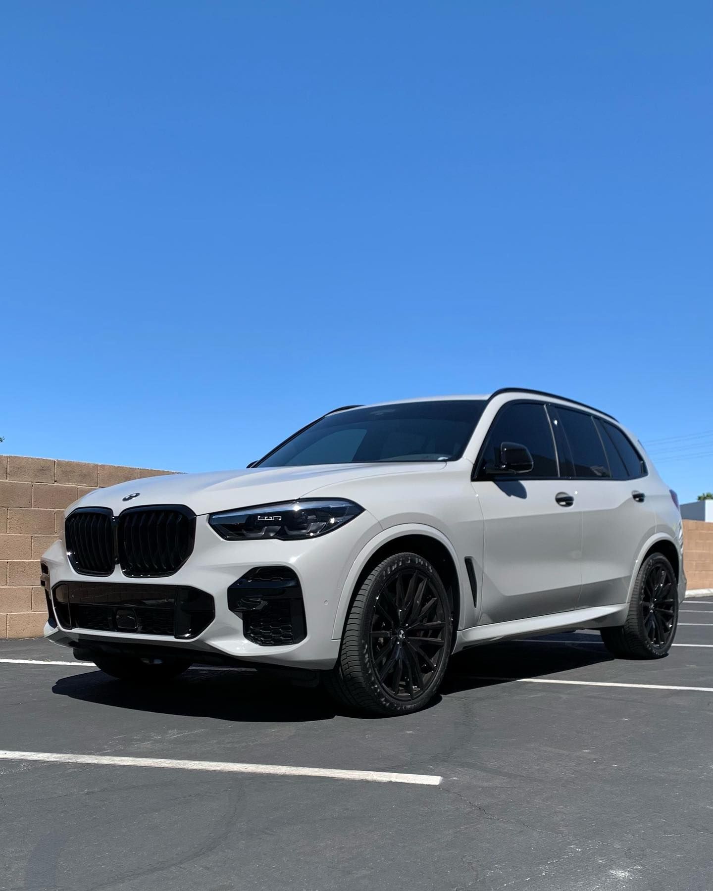 White BMW SUV parked in an empty lot under a clear blue sky