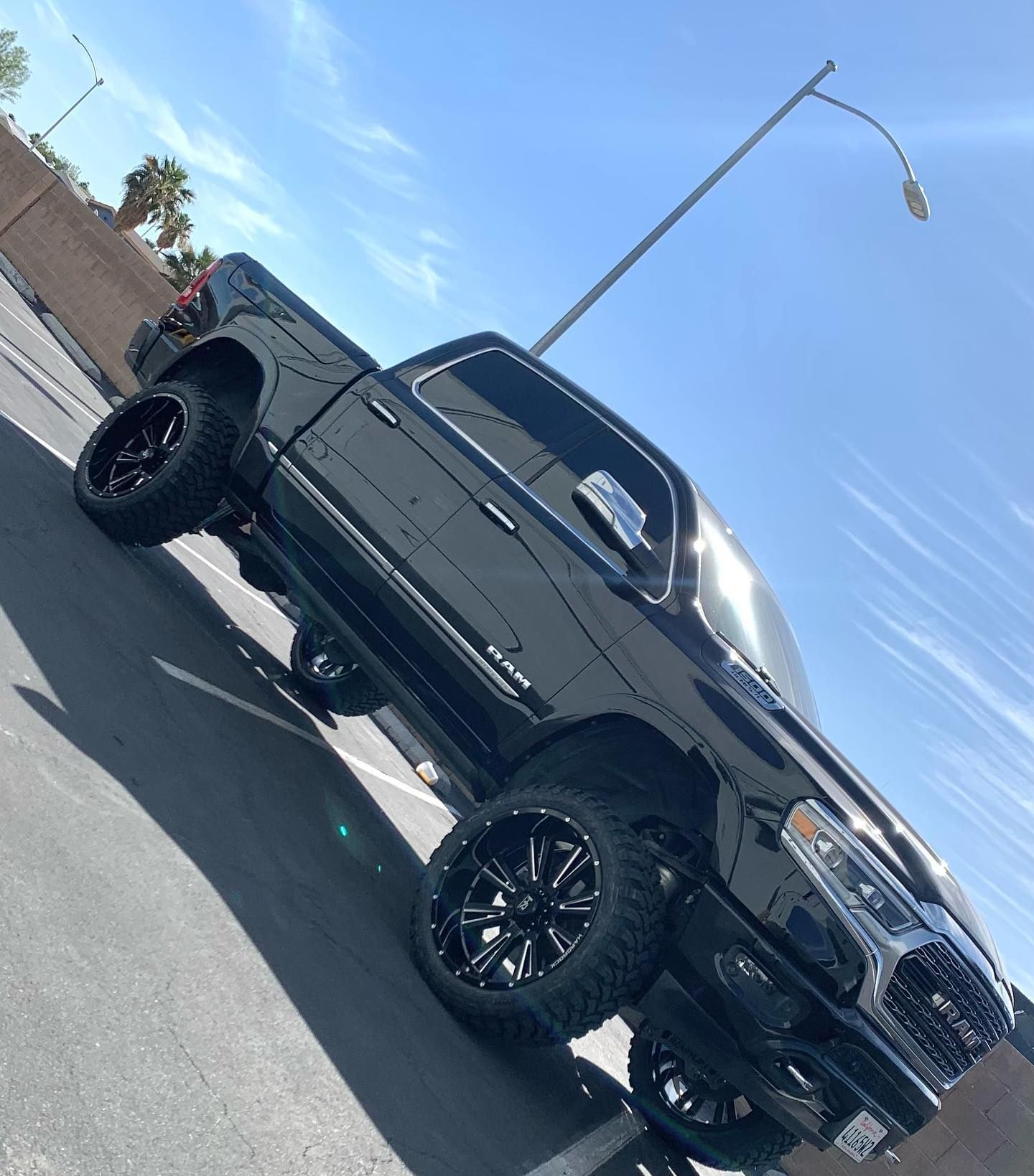 Black lifted pickup truck parked on a street under a blue sky