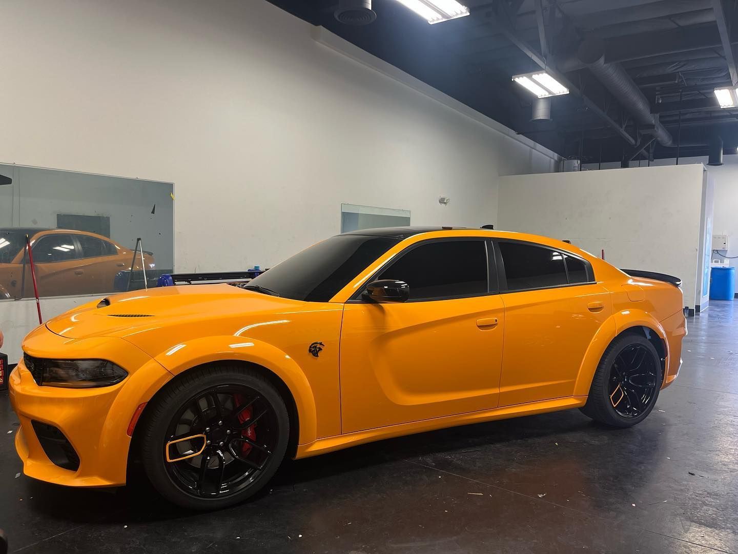 Orange sports car with black wheels parked indoors in a garage.