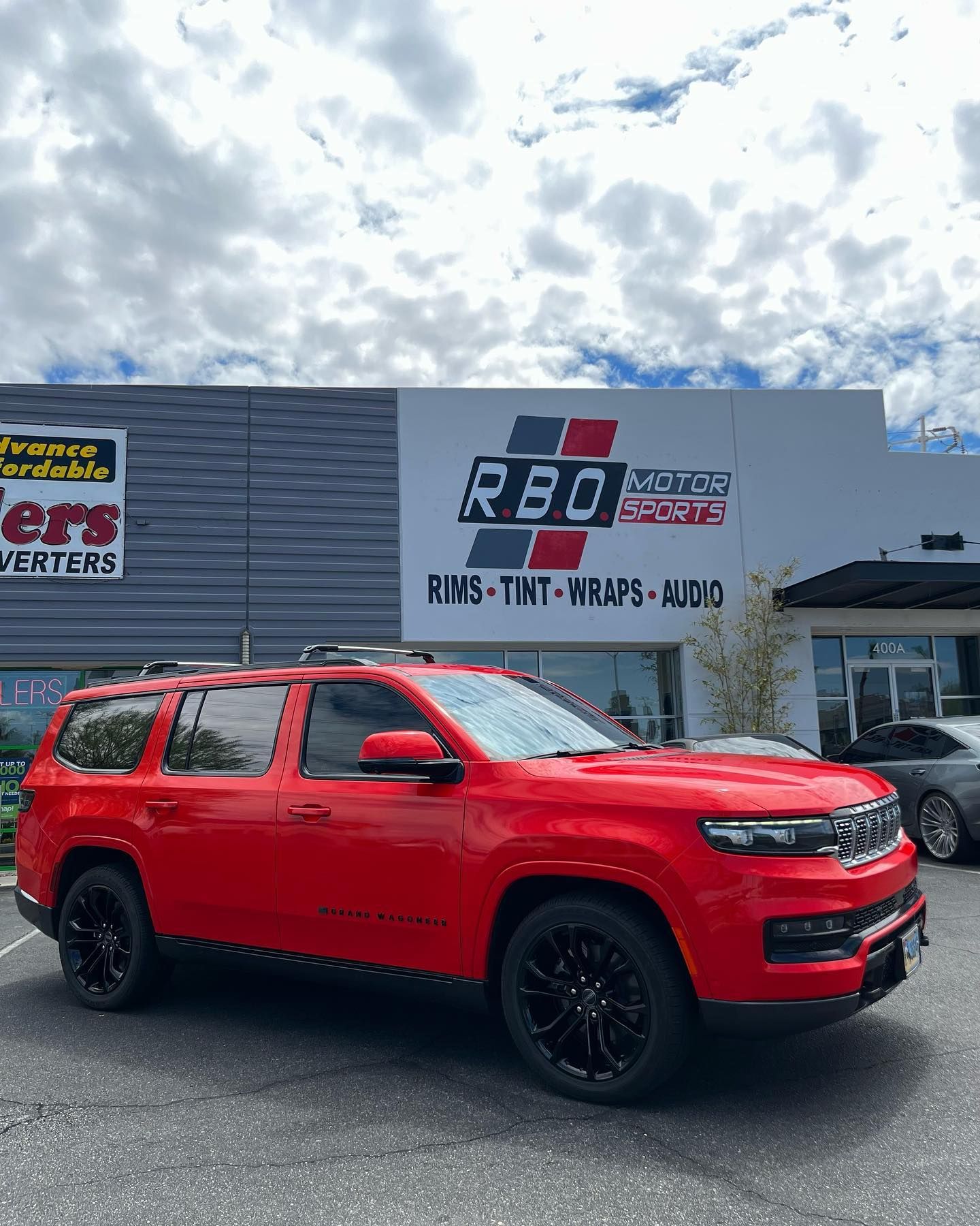 Red SUV parked outside a car dealership under a cloudy sky