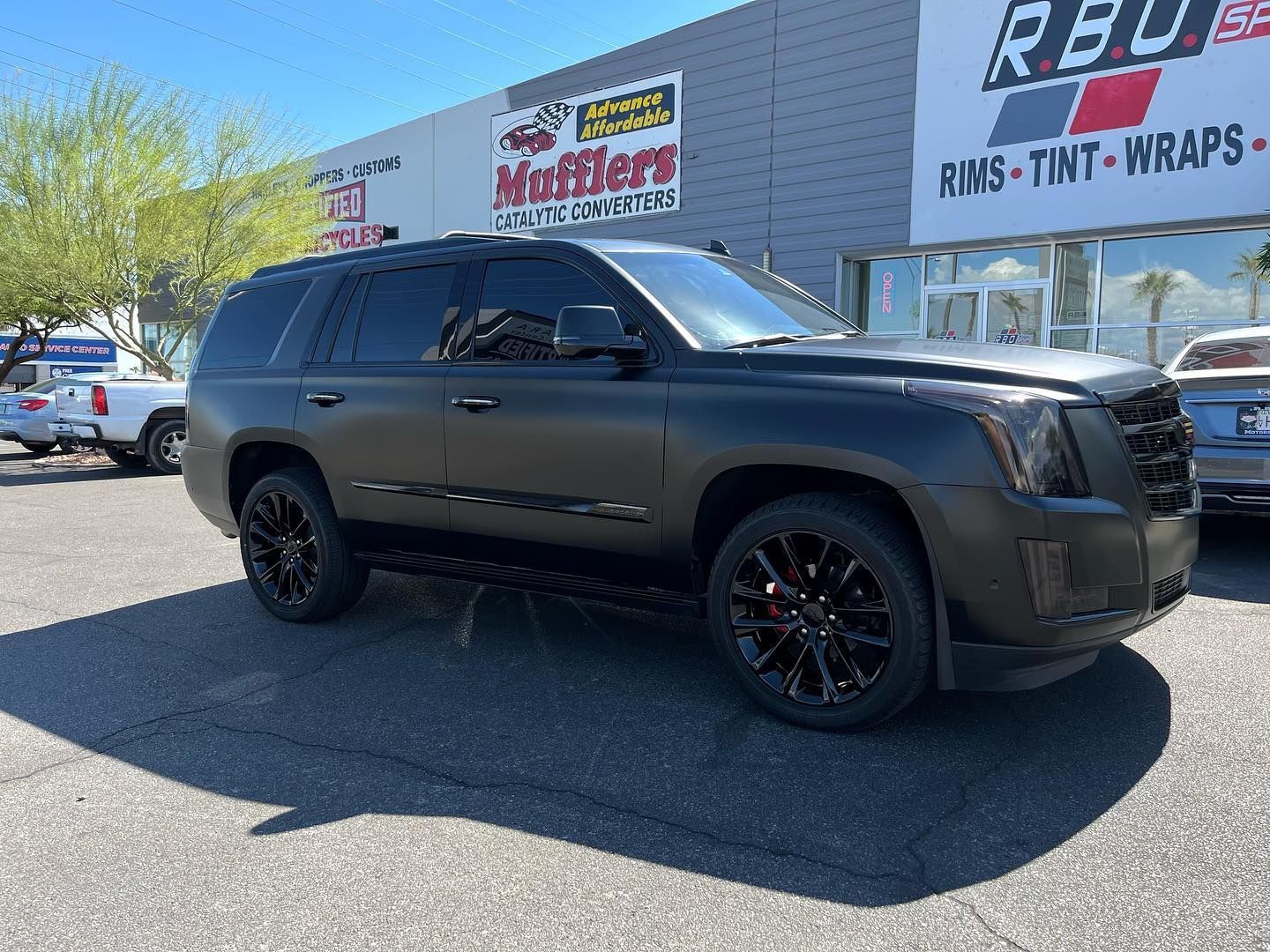 Black SUV parked outside a car customization shop on a sunny day