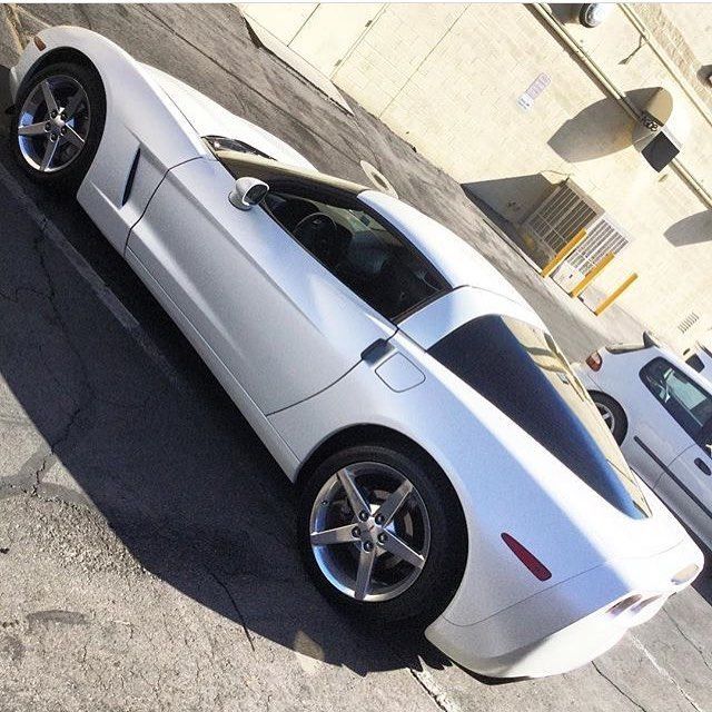 Silver sports car parked at an angle beside a concrete building in a parking lot.