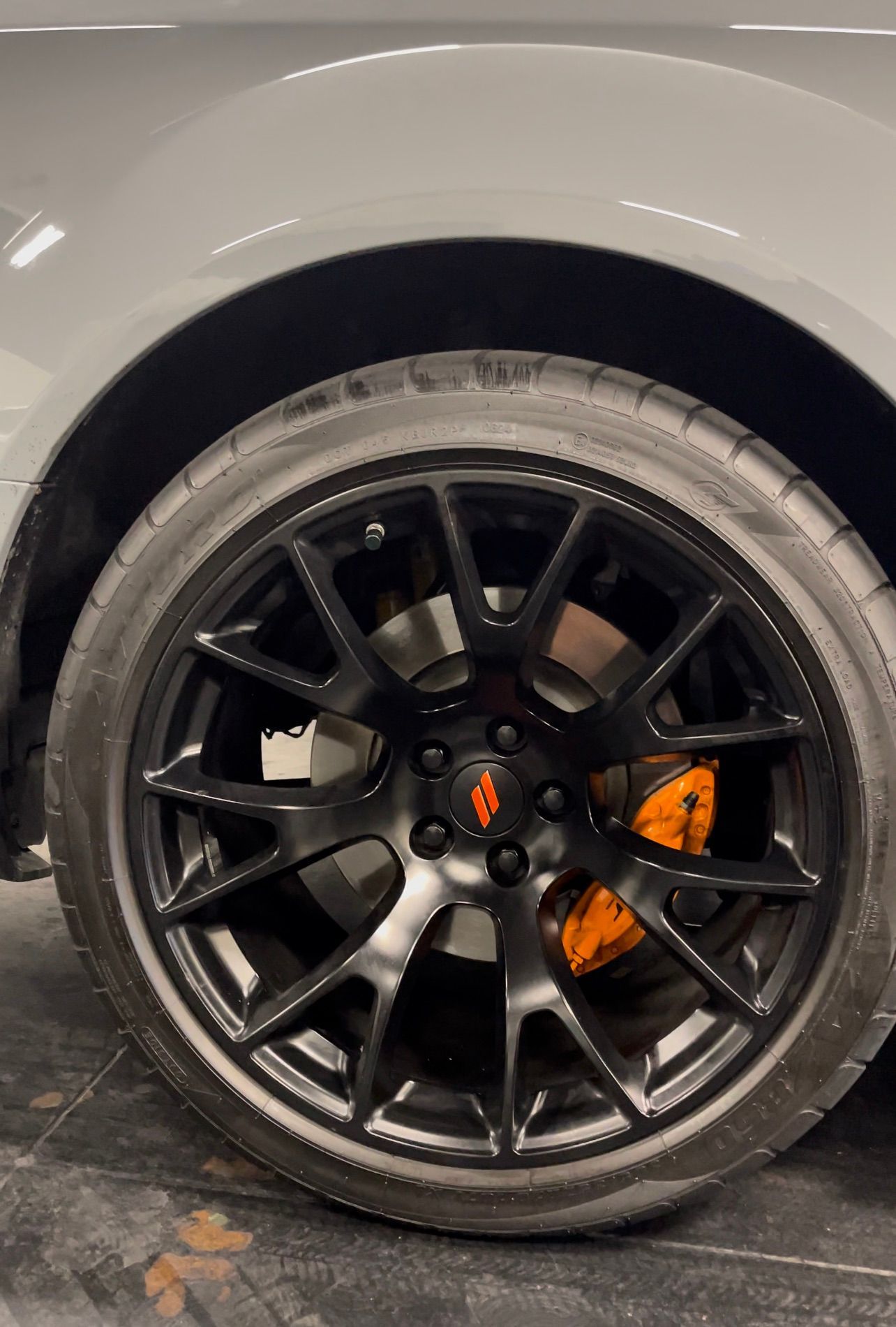 Black car wheel with alloy rim and orange brake caliper, close-up view