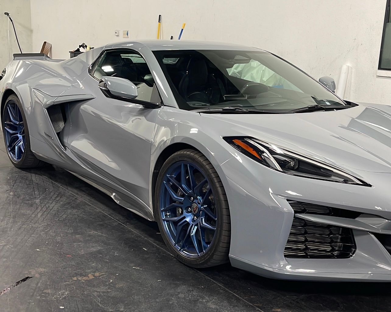 Silver sports car with blue wheels parked indoors in a garage or detailing shop