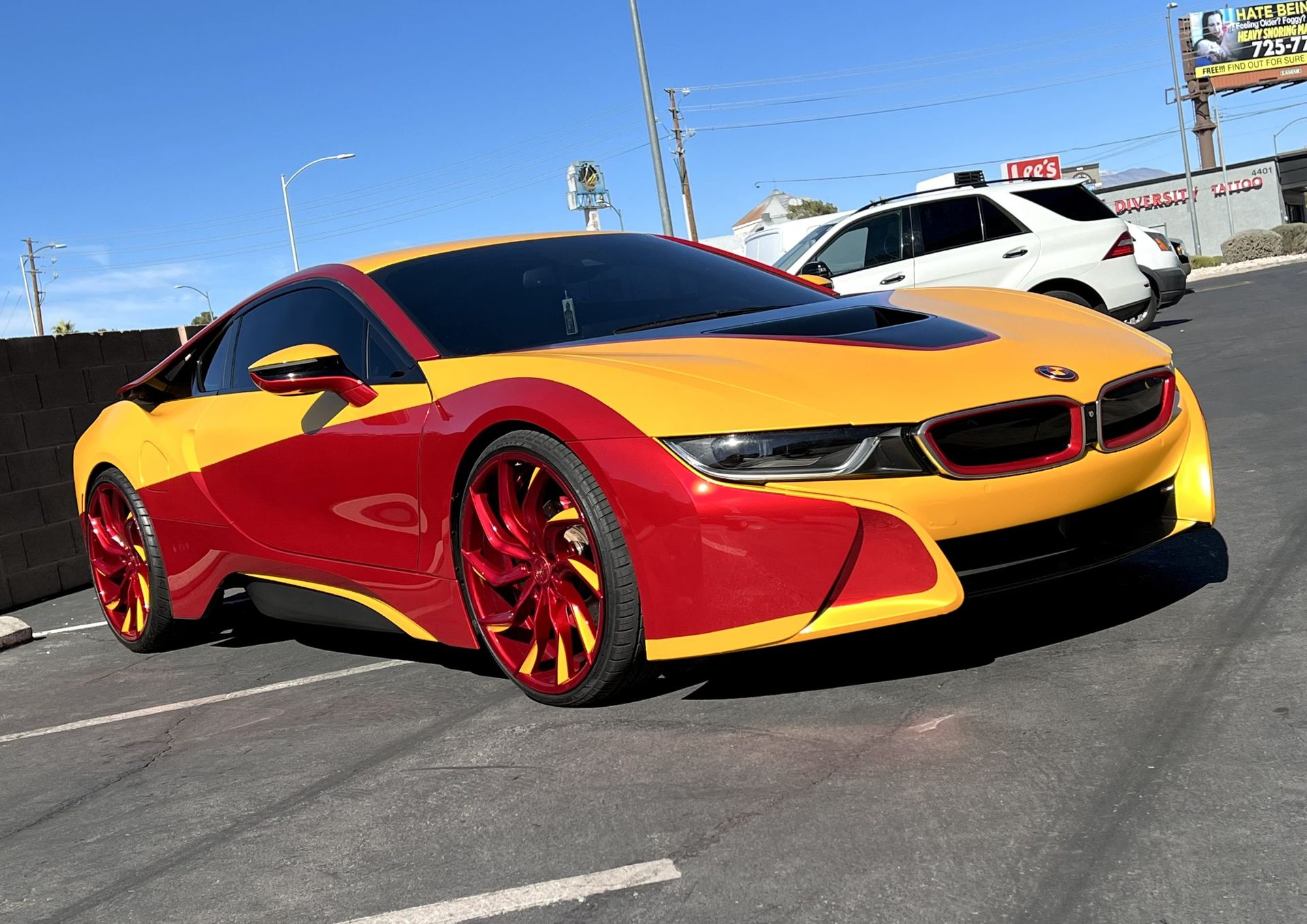 Red and yellow sports car parked in a sunny lot, viewed from the front-left side.