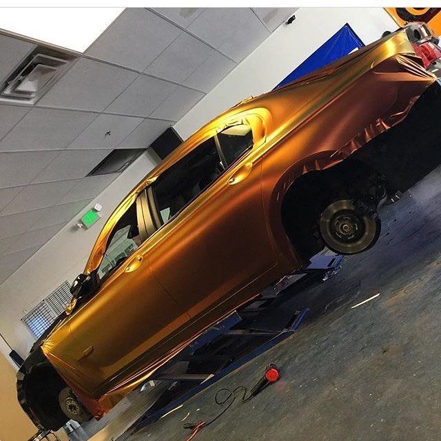 Orange car in a tilted indoor display with its wheels removed.