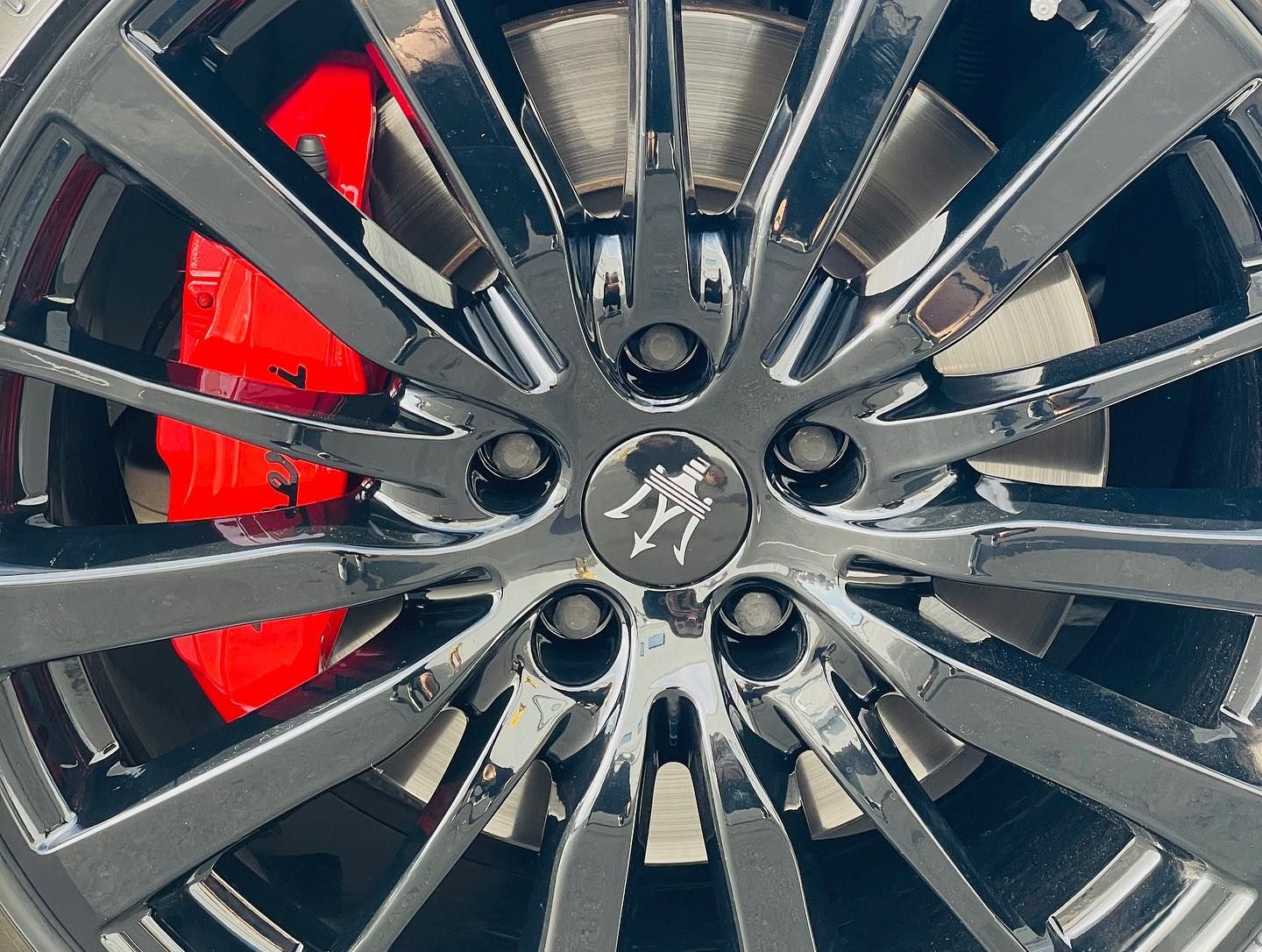 Close-up of a black alloy car wheel with red brake caliper behind it.