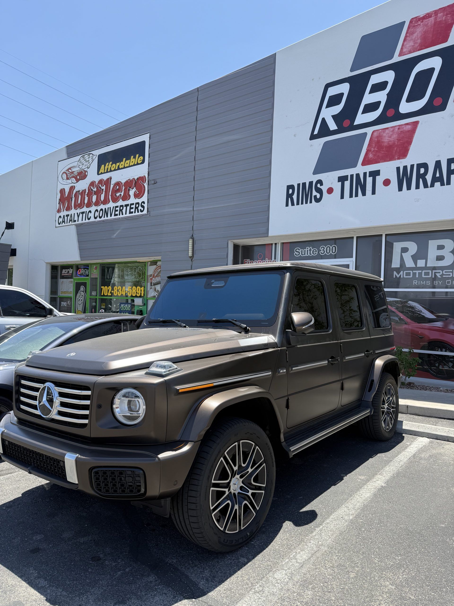 Black SUV parked outside an RBO tint and wrap shop on a sunny day