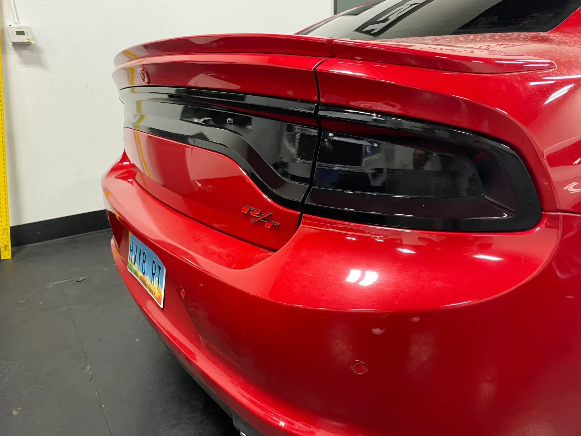 Red sports car rear with black taillights parked indoors