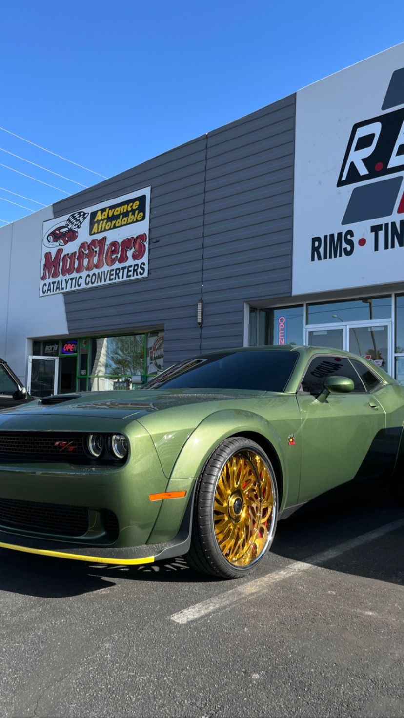 Green sports car with gold rims parked outside a tire and wheel shop