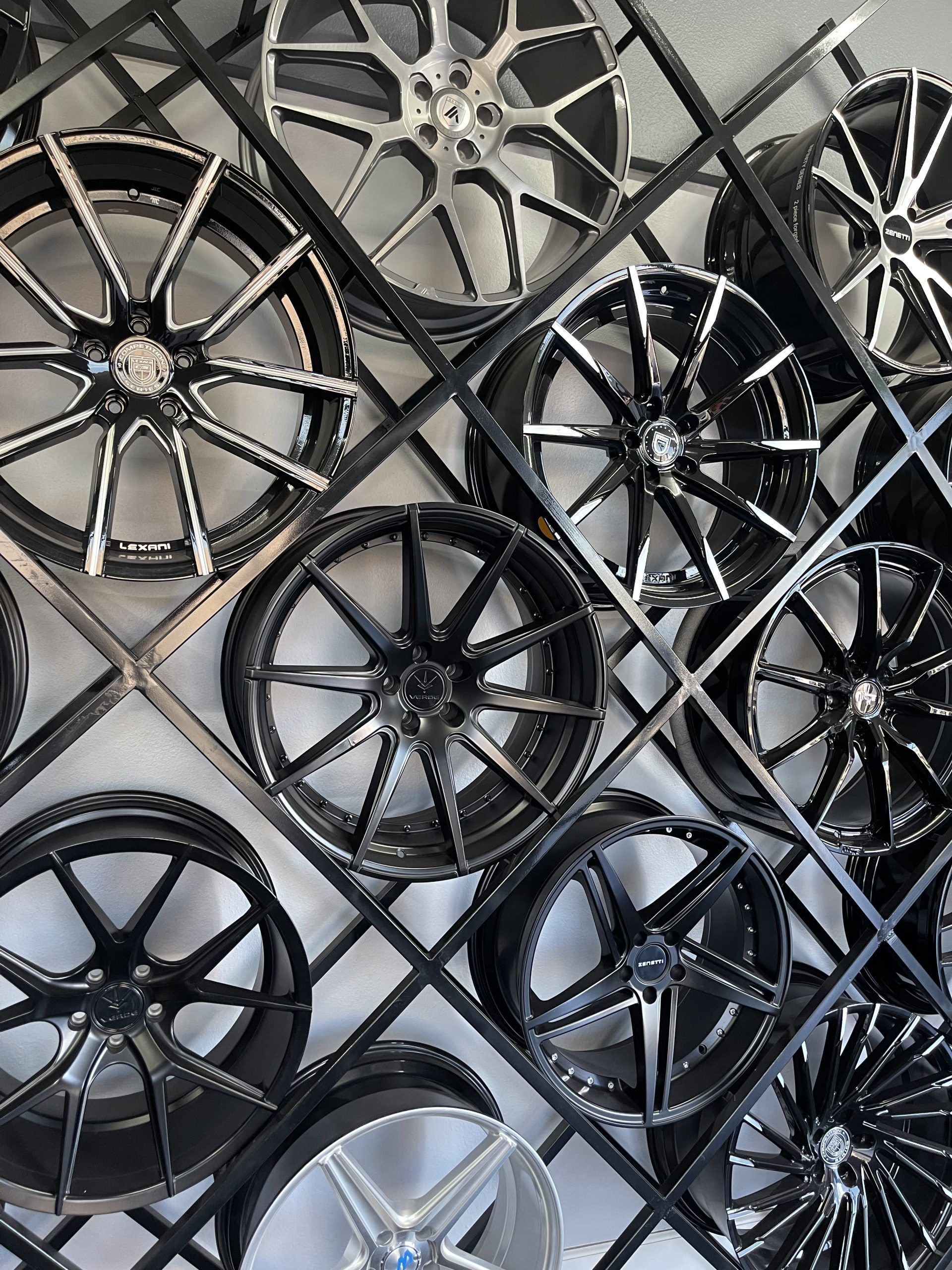 Assorted black and silver car rims displayed in a stacked shop rack