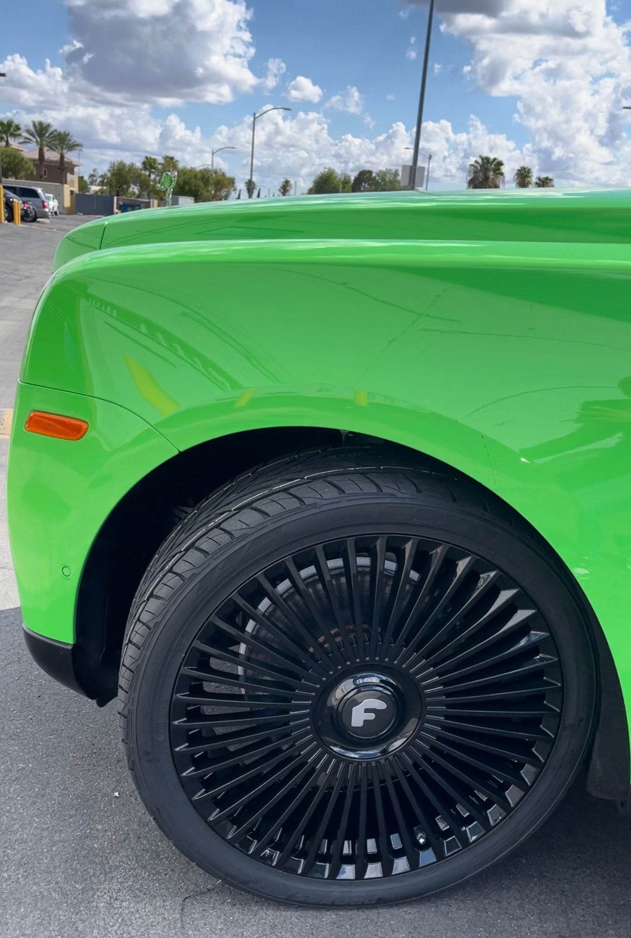 Bright green car close-up with black wheel and tire parked outdoors