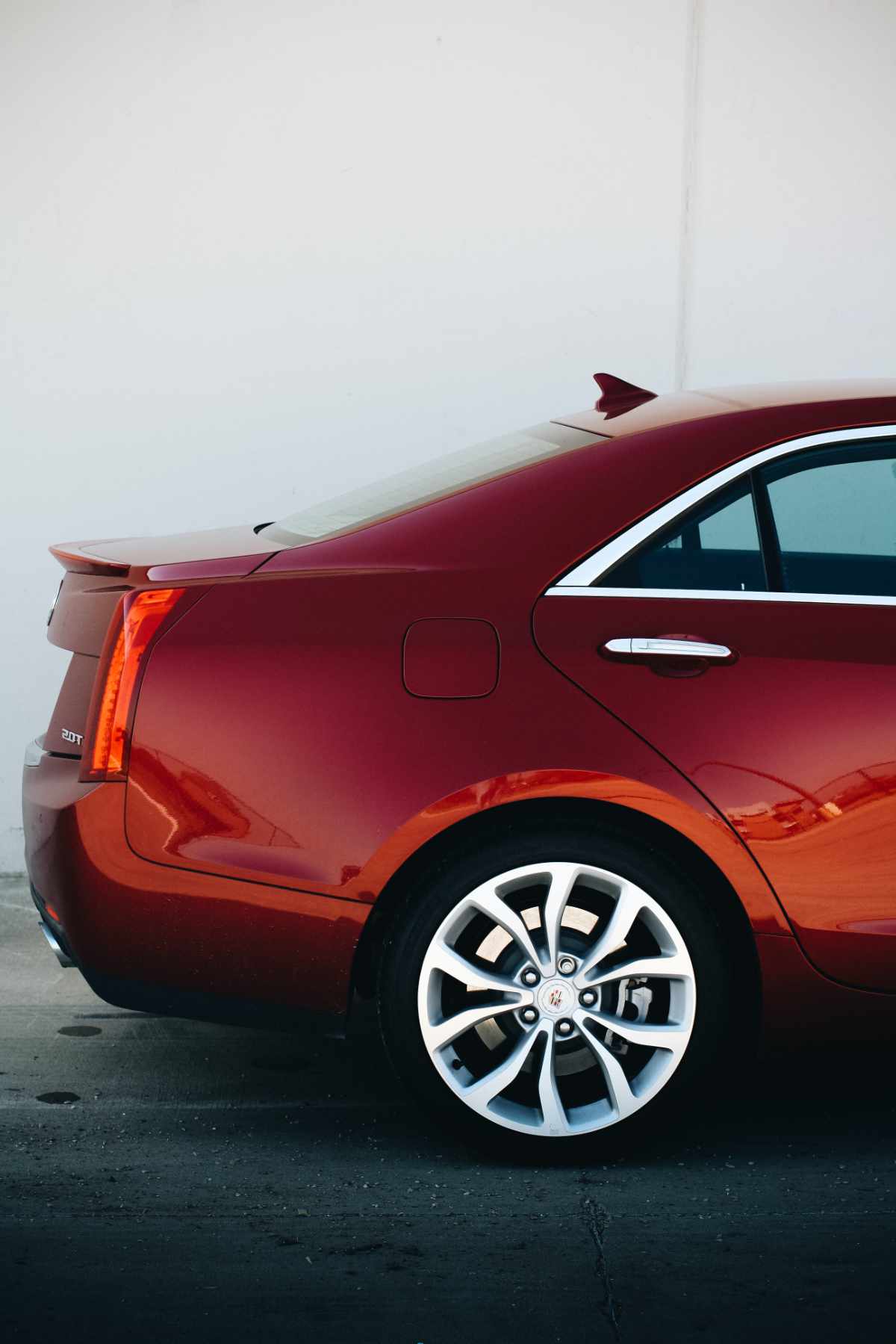 polished red car rear end against a white wall