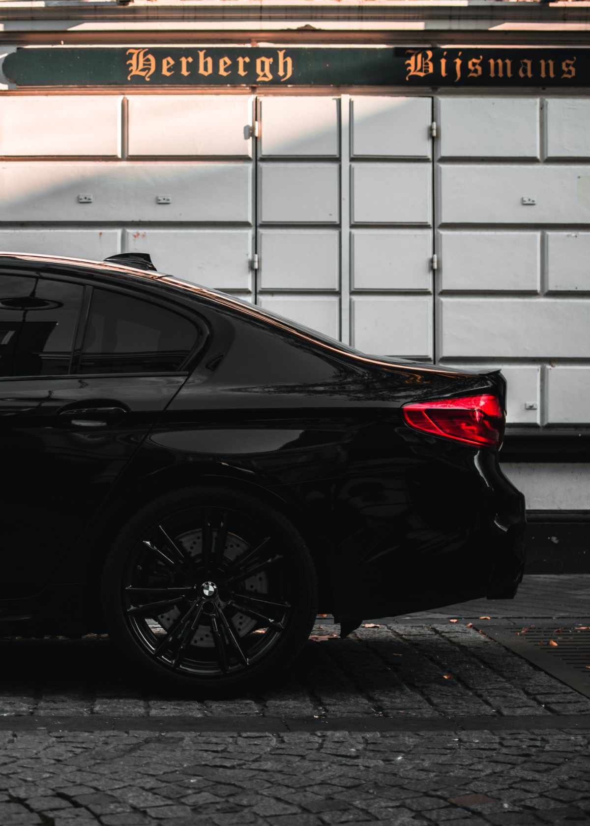 shiny rear end of a black car against a checkered wall