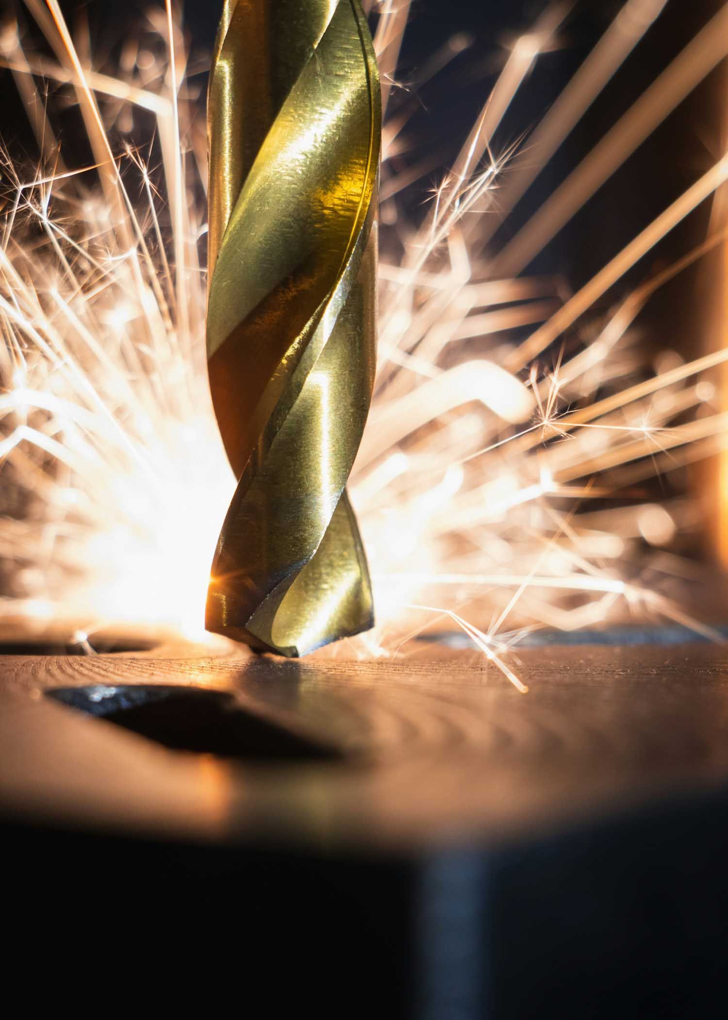 Gold drill bit creating sparks while drilling into metal