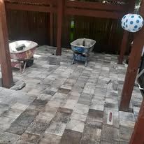 Patio with gray pavers, two potted plants in buckets, and a blue-and-white hanging ball on the right