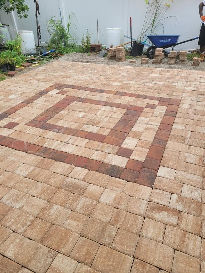 Brick-paved courtyard with a square mosaic pattern and a wheelbarrow in the background