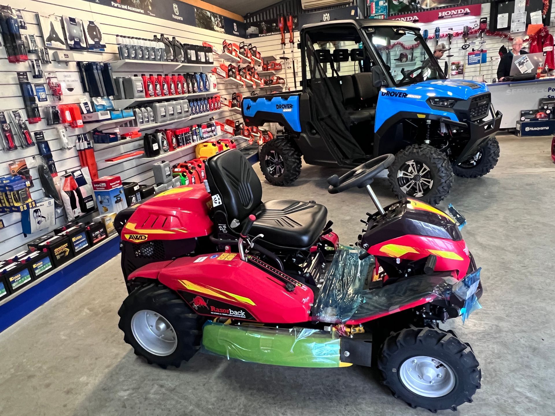 A Red Riding Lawn Mower and a Blue Off-road Vehicle Inside a Store — Gloucester Outdoor Solutions In Gloucester, NSW