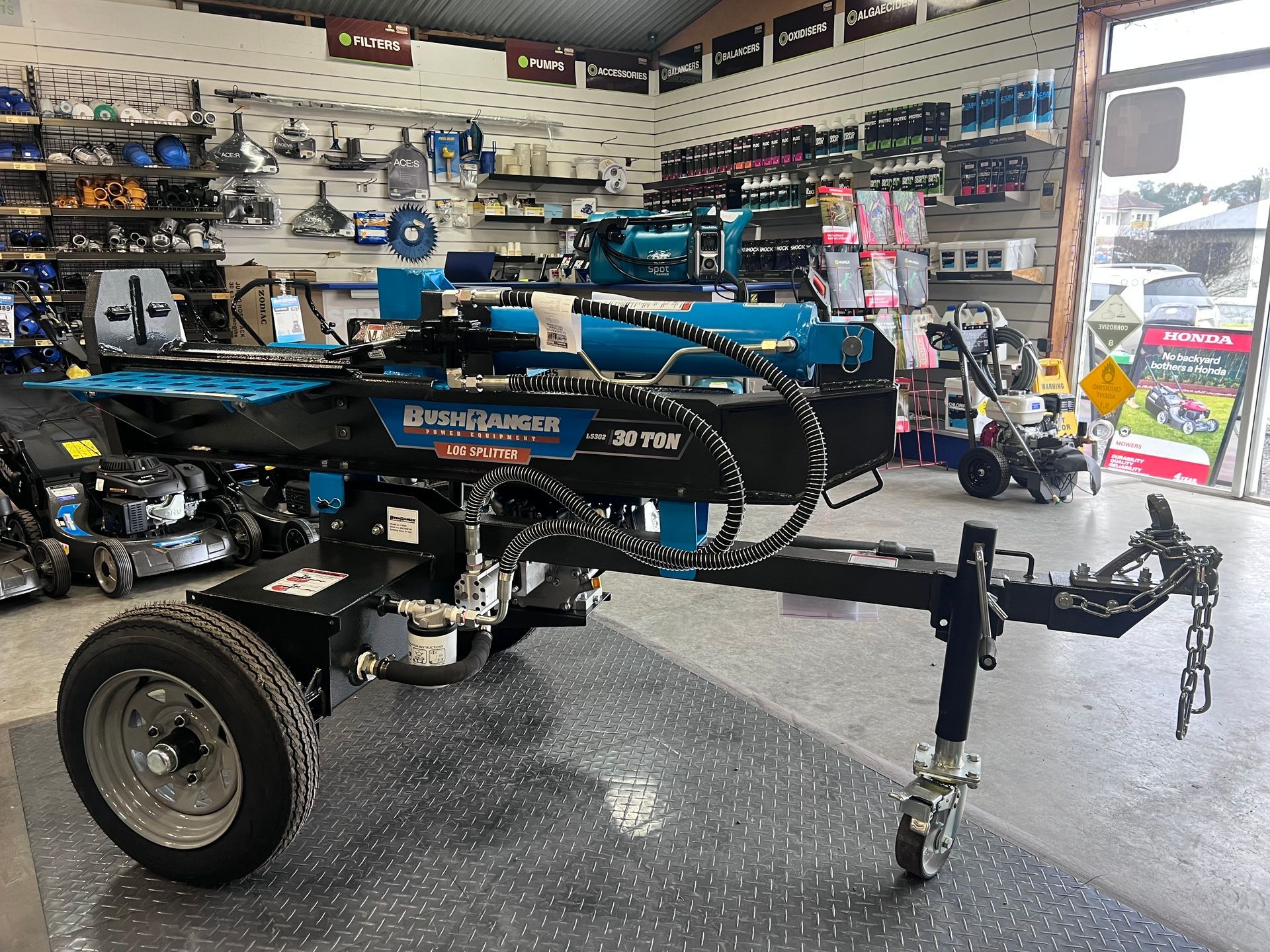 A Blue and Black Log Splitter on a Trailer Inside a Hardware Store — Gloucester Outdoor Solutions In Gloucester, NSW