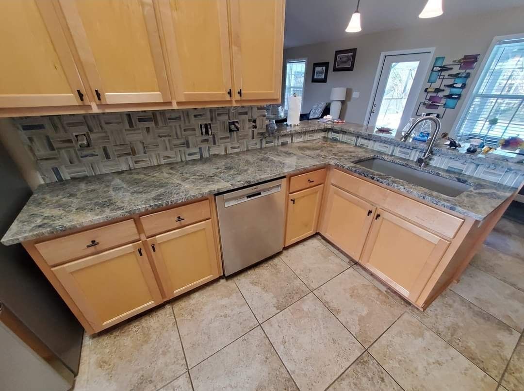 A kitchen with white cabinets , stainless steel appliances , and a large island.