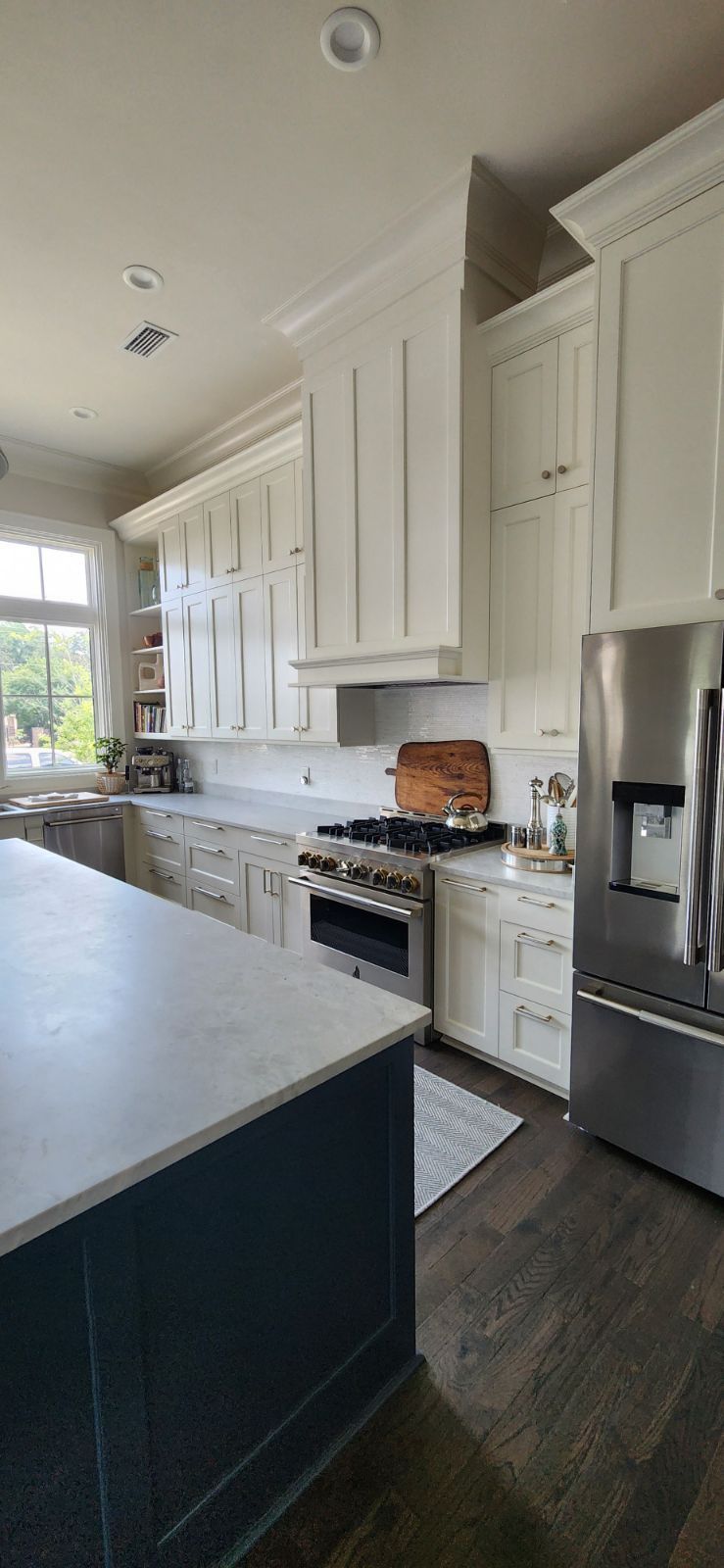A kitchen with white cabinets , stainless steel appliances , and a large island.