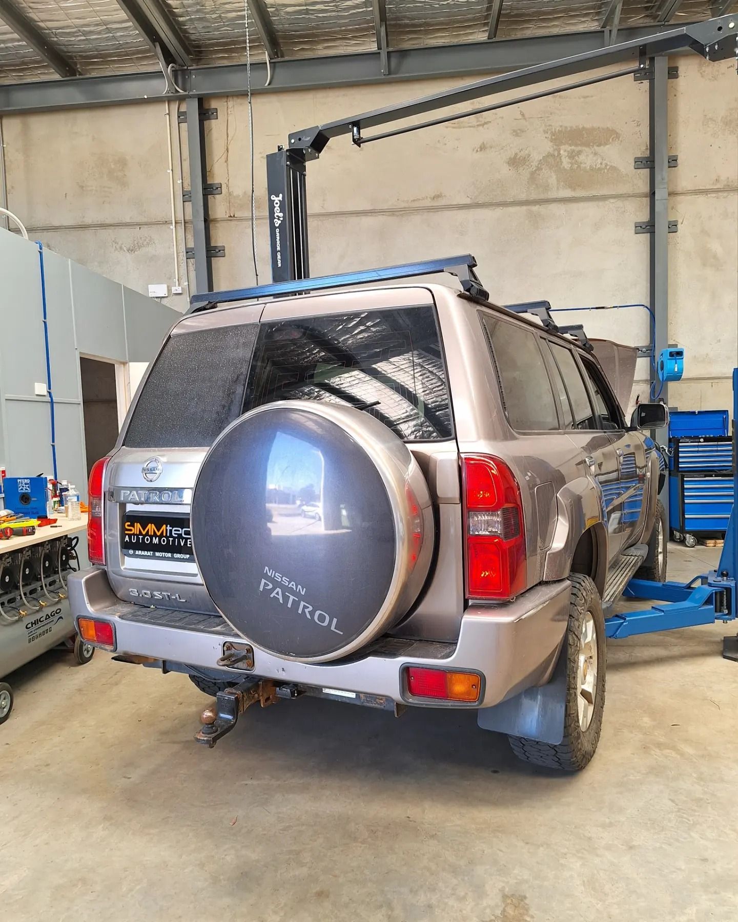 A nissan pathfinder is sitting on a lift in a garage.
